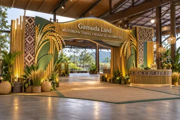 Gamuda Land kaamatan celebration with a clear walk-through bamboo-inspired harvest welcome arch with paddy motifs, restrained Sabah-inspired woven decorative panels and a community information counter