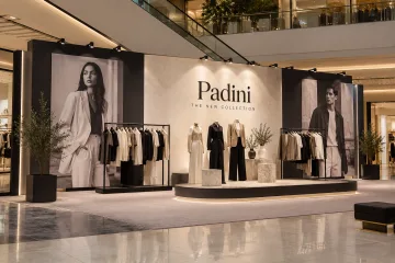 Padini fashion collection launch with clothing rails, low runway platform, printed editorial panels and launch media wall
