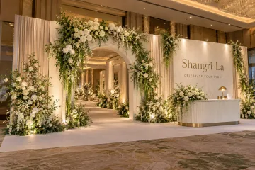 Shangri-La wedding showcase with a generous walk-through floral wedding entrance arch, satin-lined side panels and an elegant bridal welcome counter